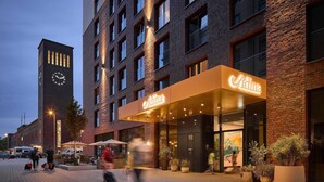 A hotel with a prominent clock tower, a well-lit entrance, and outdoor seating areas.