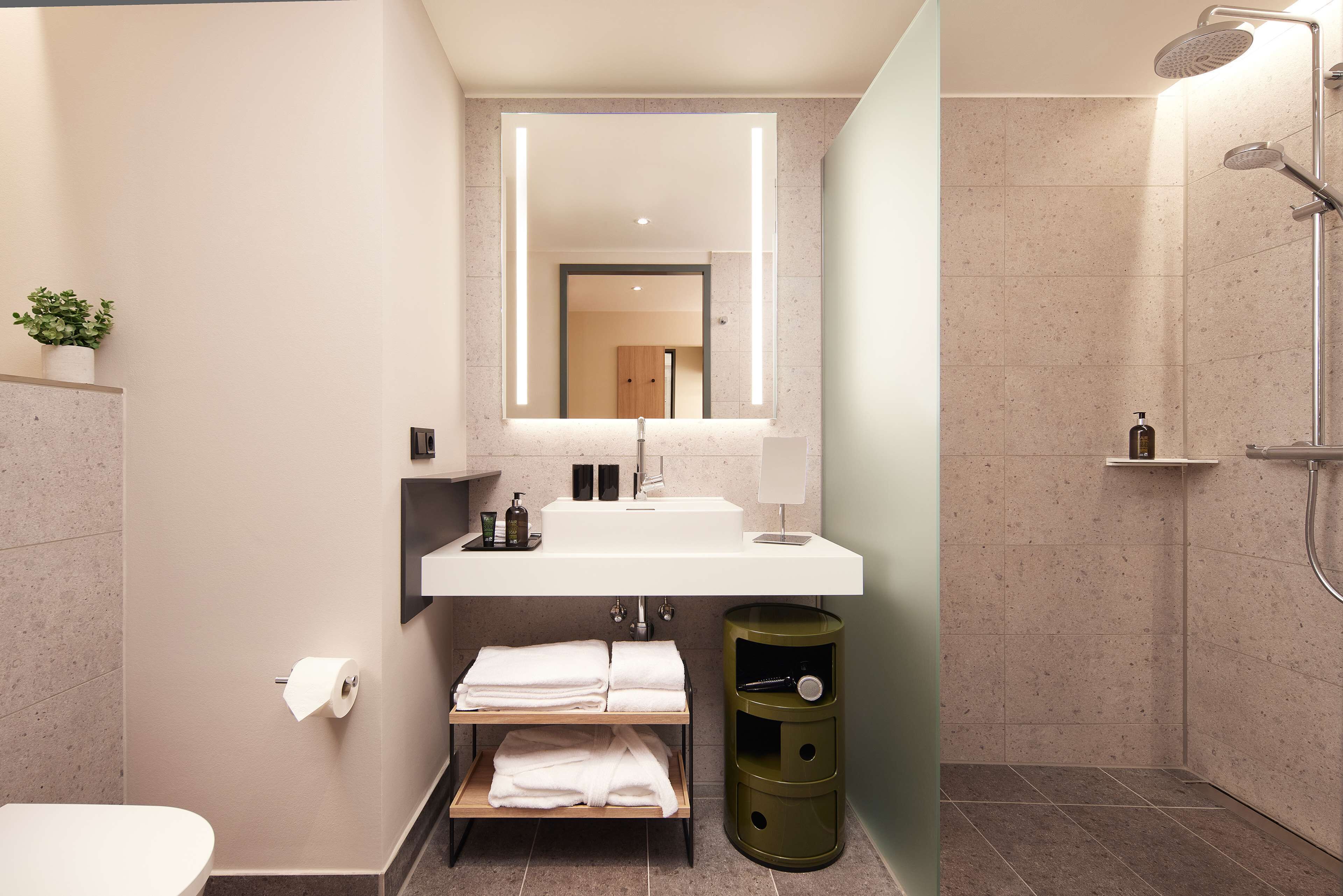 A modern bathroom with a white sink, a mirror, a towel rack, and a shower.