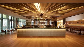 A modern bar area with a central counter, wooden flooring, and pendant lighting.