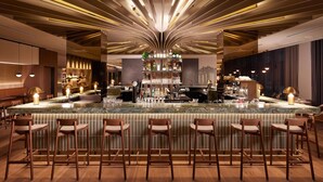 A bar area with a central island, bar stools, and a well-lit ceiling with linear lighting.