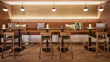 Interior de restaurante con cabinas de madera, sillas con asientos acolchados en verde e iluminación colgante.