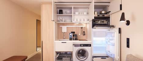 Cocina compacta con lavadora y secadora integradas, comedor y una banca.
