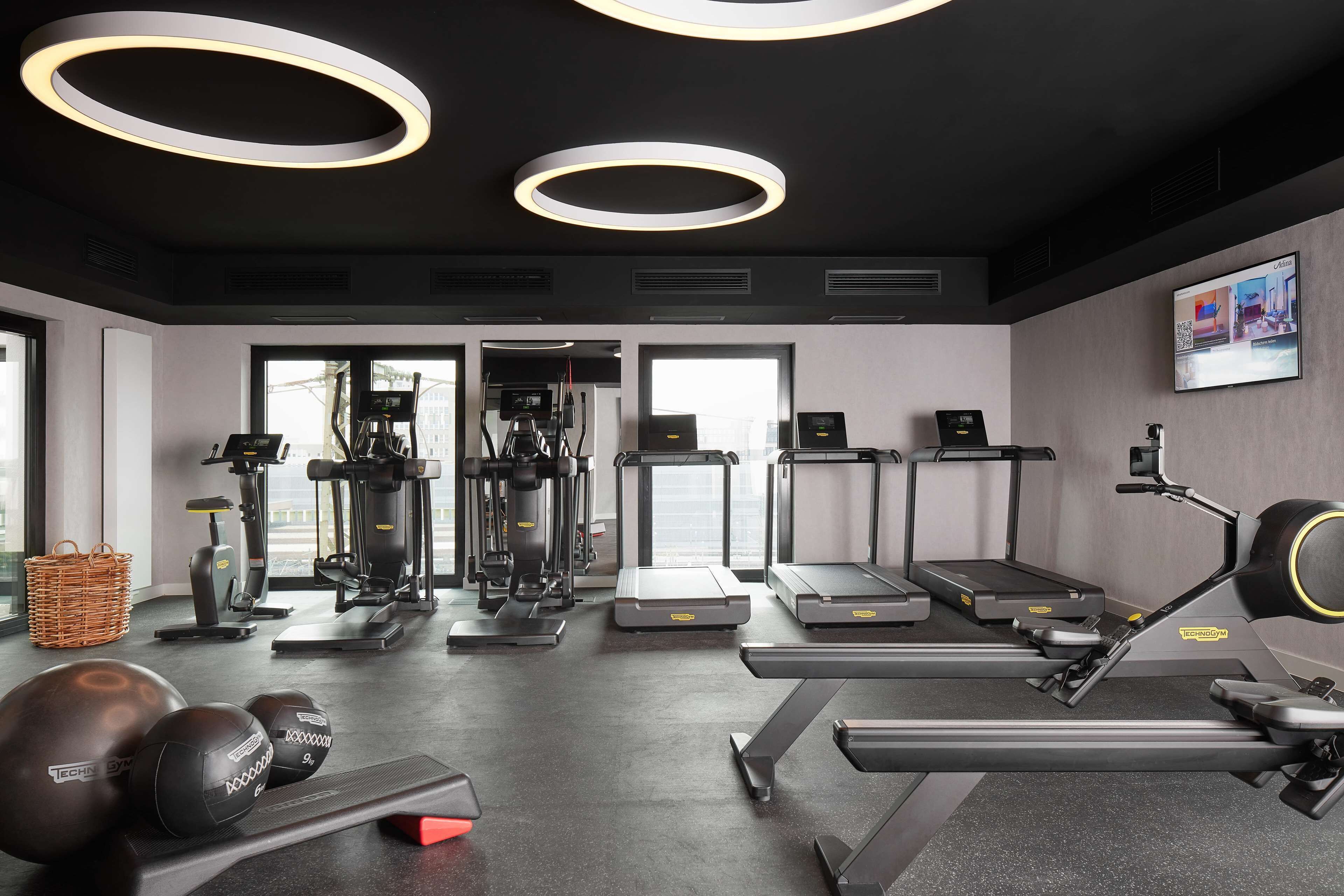 Une salle de sport moderne équipée de tapis de course, de vélos elliptiques et de poids libres.