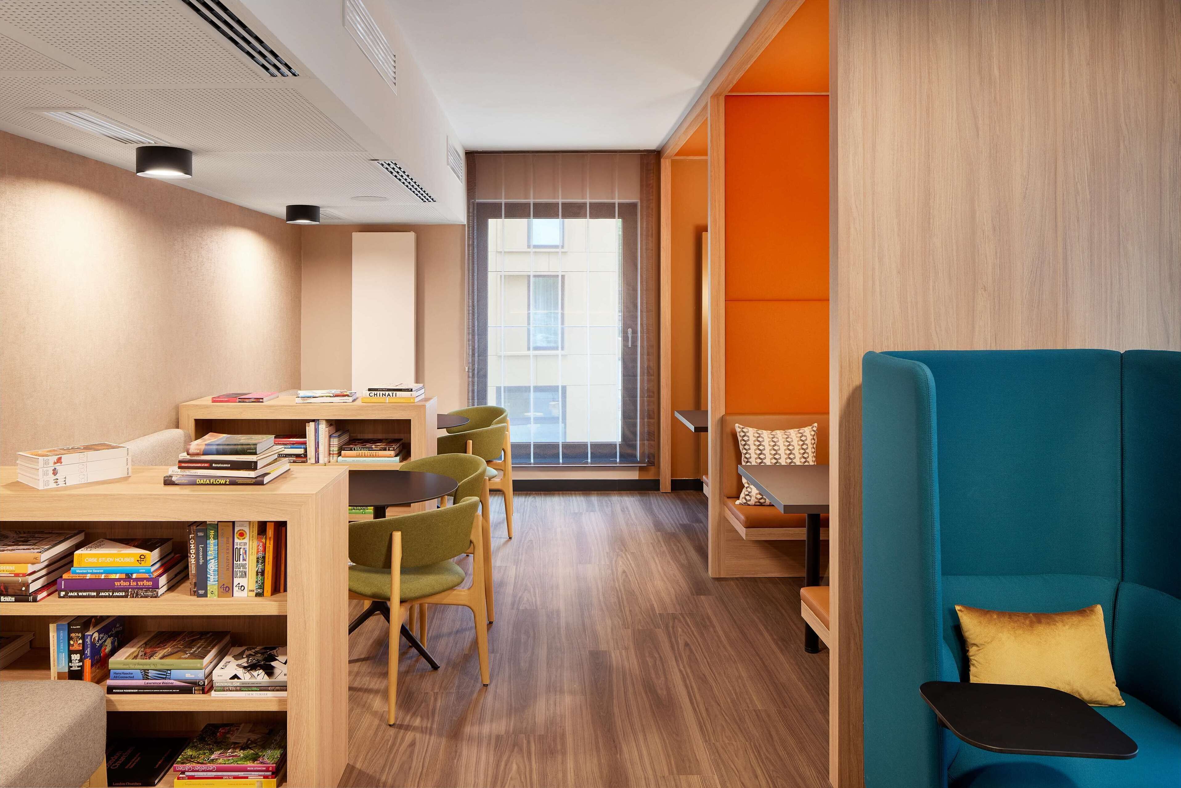 A modern reading area with a bookshelf, chairs, and a sofa.