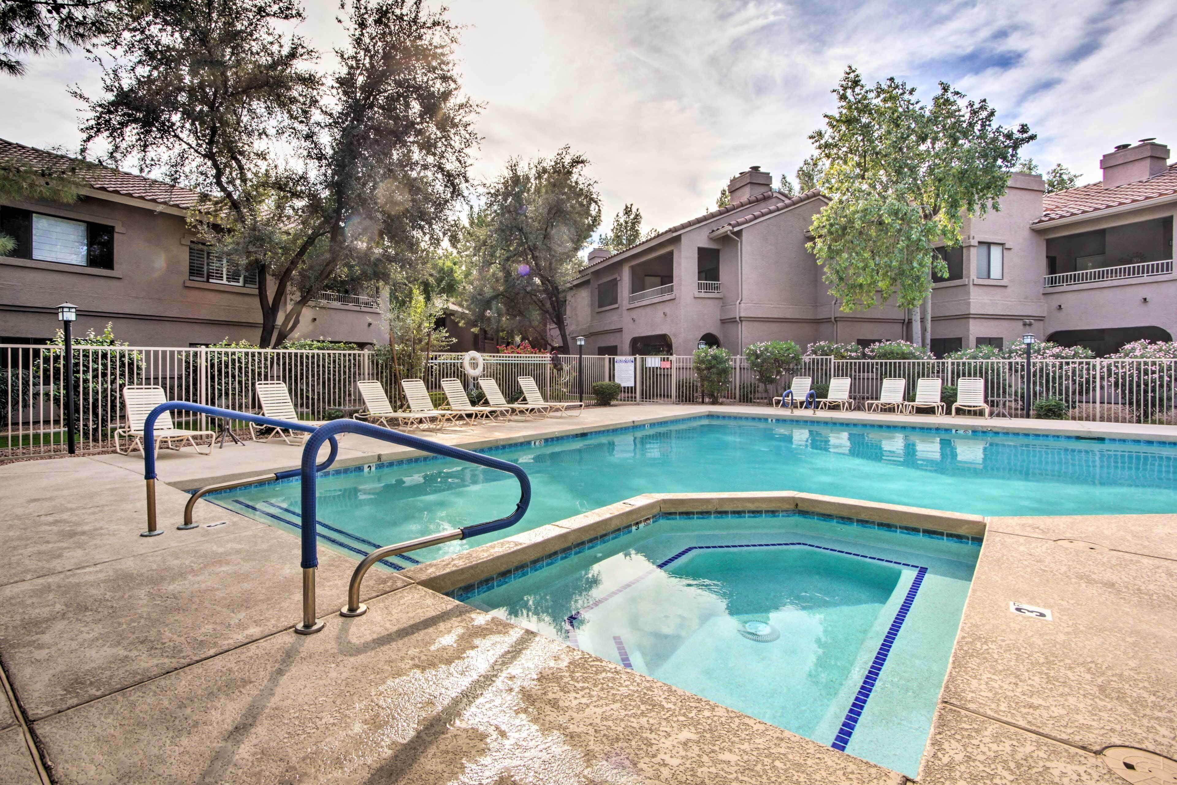 A rectangular swimming pool with a blue border, surrounded by a white fence, and adjacent to a building with balconies.