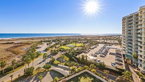 Un hôtel doté d’un parking, de palmiers et offrant une vue sur la plage.