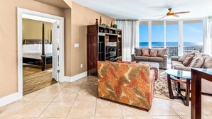 Une chambre d’hôtel avec un balcon, un lit, un canapé, une table basse et un téléviseur.