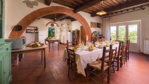 A dining area with a brick archway, wooden ceiling beams, and a table set for six with chairs. - Independent villa with WIFI, private pool, A/C, close to Cortona! (Castiglion Fiorentino)