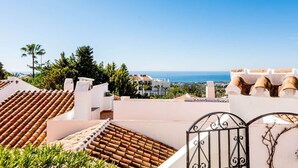 Un área residencial costera con tejados de tejas rojas, paredes blancas y una vista despejada del mar.