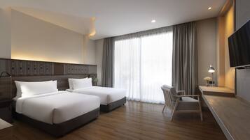 Habitación de hotel con dos camas, un escritorio, una silla y un televisor.