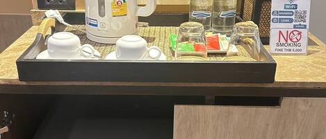 Minibar com máquina de café, garrafas e dispensador de água.