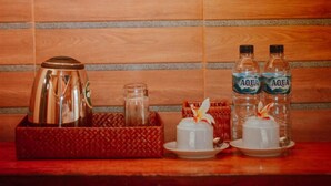 A tray with a coffee pot, a glass jar, two water bottles, and a small white cup with a flower on a wooden surface. - Watu Jineng by WizZeLa (Penida Island)