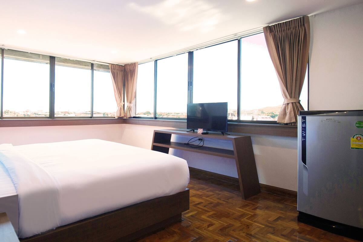 Een hotelkamer met een bed, een bureau, een televisie en een koelkast.