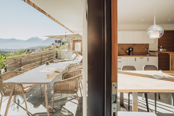 A modern kitchen with wooden cabinets, a coffee machine, and a dining area with a table and chairs.