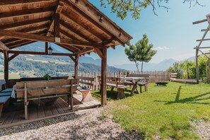Un belvédère en bois, doté de bancs et de tables, qui offre une vue sur un paysage montagneux.