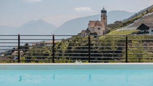 A swimming pool with a view of a church and vineyards.