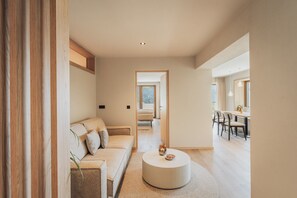 A modern living room with a sofa, a round coffee table, and a dining area with chairs and a table.