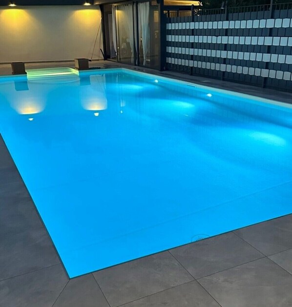 Une piscine éclairée de lumière bleue.