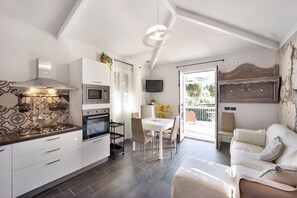 Une cuisine moderne équipée d’une cuisinière, d’un four et d’un four à micro-ondes, un coin repas avec une table et des chaises, et un salon avec un canapé et un téléviseur.