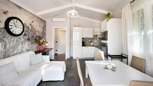 Una cocina moderna con armarios blancos, un comedor con mesa blanca y una sala de estar con sofá blanco.