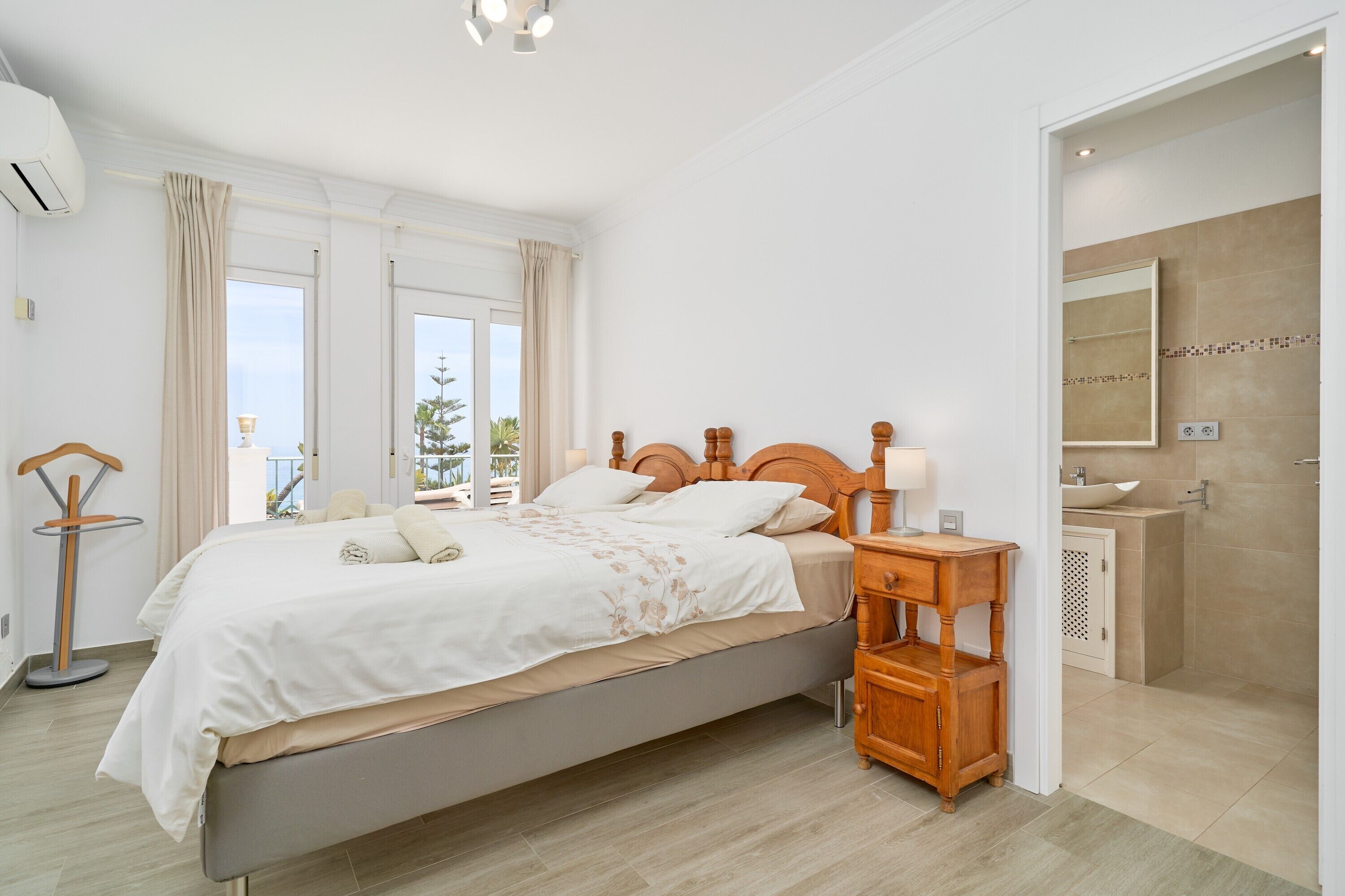 A bedroom with a bed, bedside table, and a view of the outside.