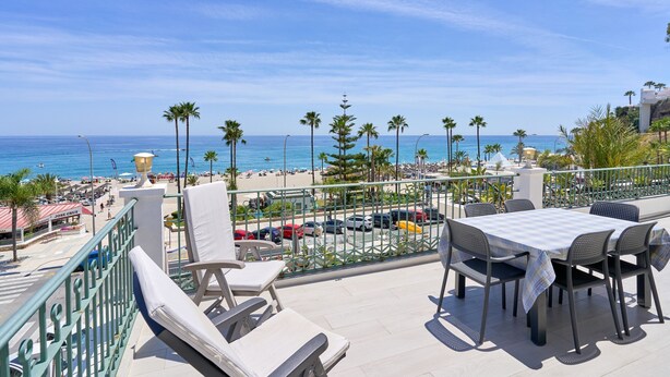 A terrace with a table and chairs, overlooking a beach and ocean. - Apartment 'Wonderful Penthouse' with Garden, Terrace, Wi-Fi & A/C (Nerja)