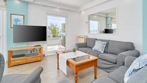 A living room with a grey sofa, a wooden coffee table, a flat-screen TV on a wooden stand, and a balcony with a view. - Apartment 'Wonderful Penthouse' with Garden, Terrace, Wi-Fi & A/C (Nerja)