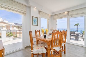 Un coin repas avec une table et des chaises, une bouteille de vin et un vase de fleurs.