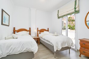 Une chambre avec deux lits, une table de chevet, une commode et une fenêtre donnant sur un beau paysage.