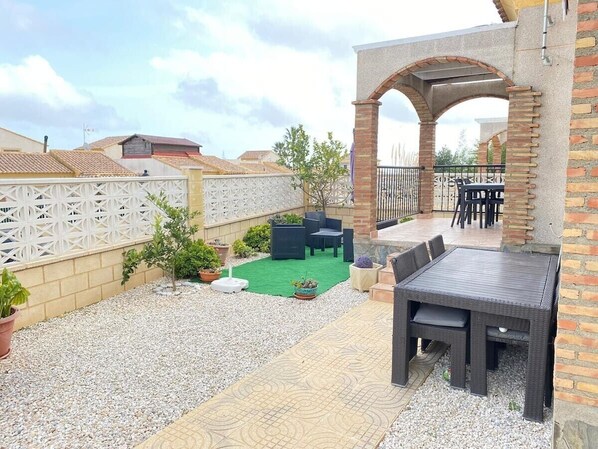 A patio with outdoor furniture, a brick wall, and a white fence.