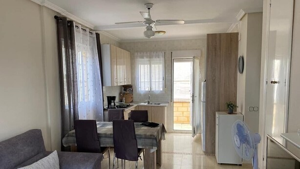 A compact living space with a dining area, kitchenette, and a ceiling fan. - Bungalow "Alberca La Nucia" with Mountain view, Terrace & Wi-Fi (polop)