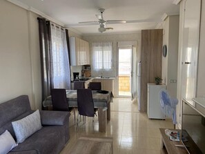A compact living space with a dining area, kitchenette, and a ceiling fan.