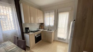A compact kitchen with a dining area, a coffee maker, and a refrigerator. - Bungalow "Alberca La Nucia" with Mountain view, Terrace & Wi-Fi (polop)