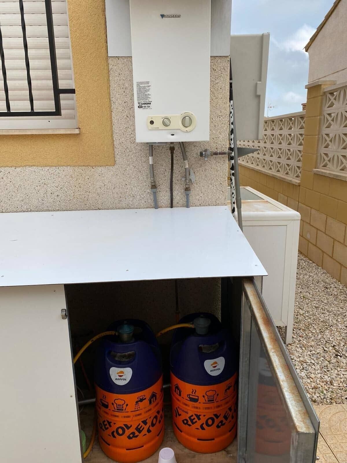 A water heater, two gas cylinders, and a white cabinet.