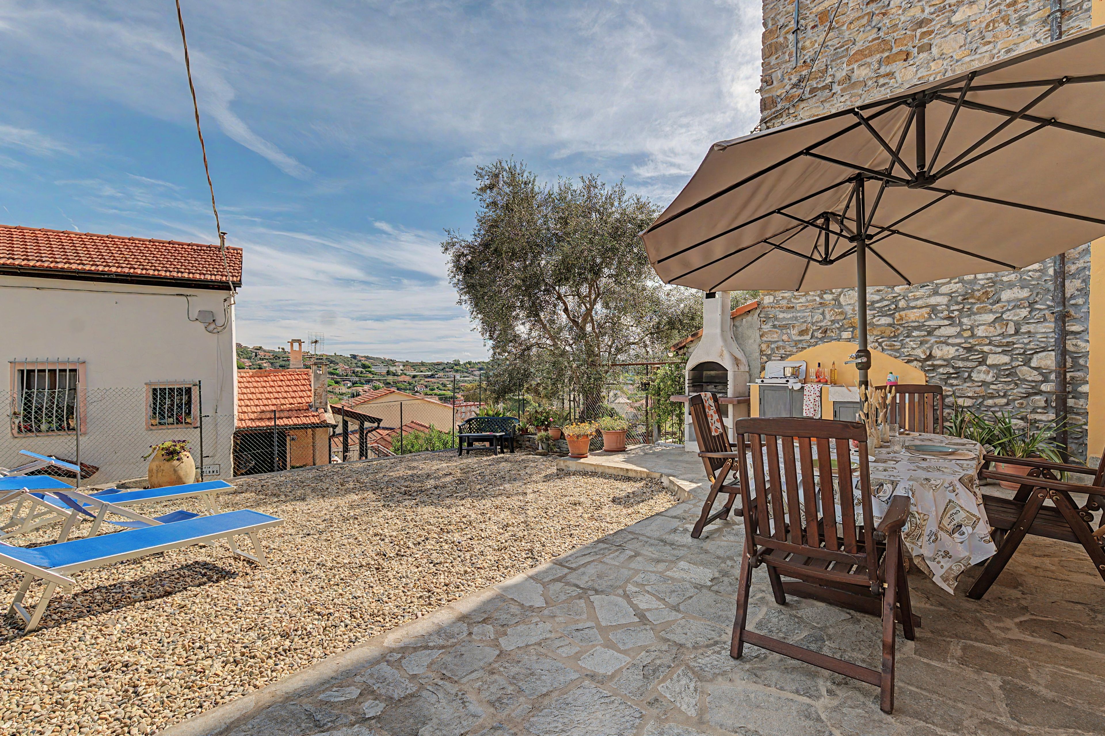 Un patio con tavolo, sedie e zona barbecue.