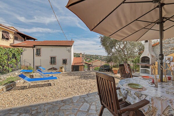 A patio area with outdoor seating, a table set for dining, and a view of the surrounding neighborhood.