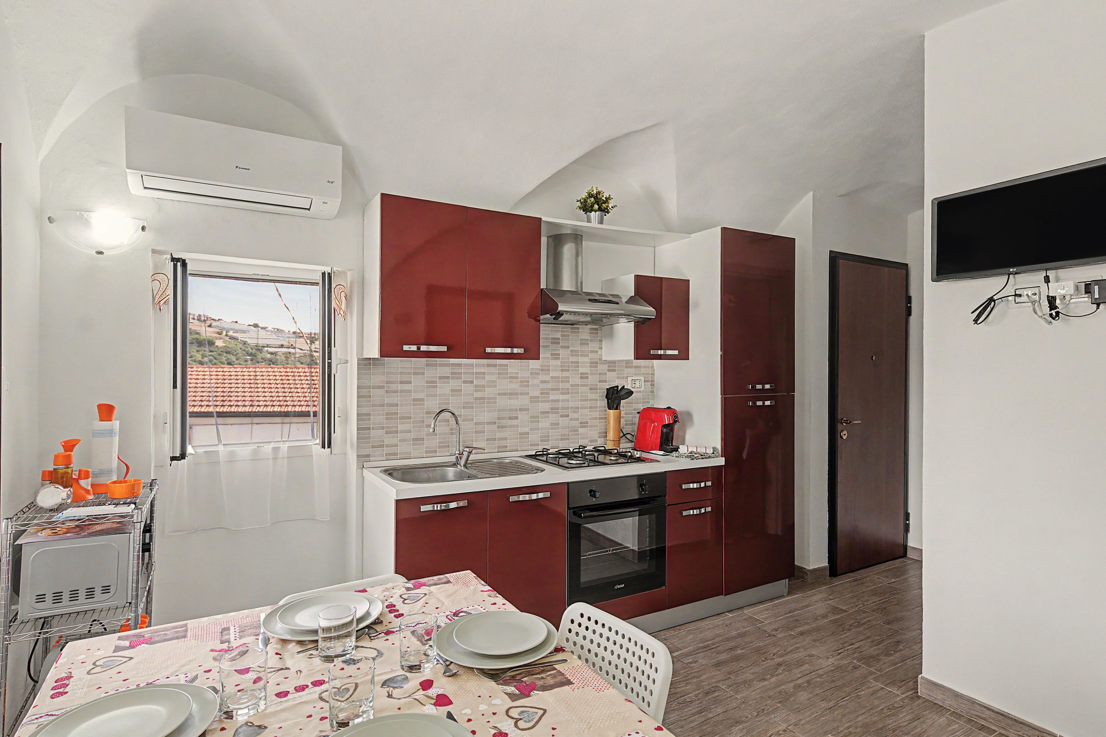 Une cuisine compacte équipée d’une cuisinière à gaz, d’un four et d’un coin repas avec une table dressée pour deux personnes.