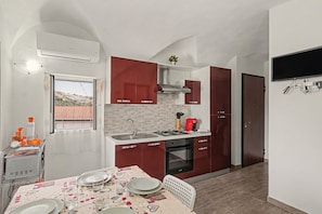 A compact kitchen with a gas stove, oven, and a dining area with a table set for two.