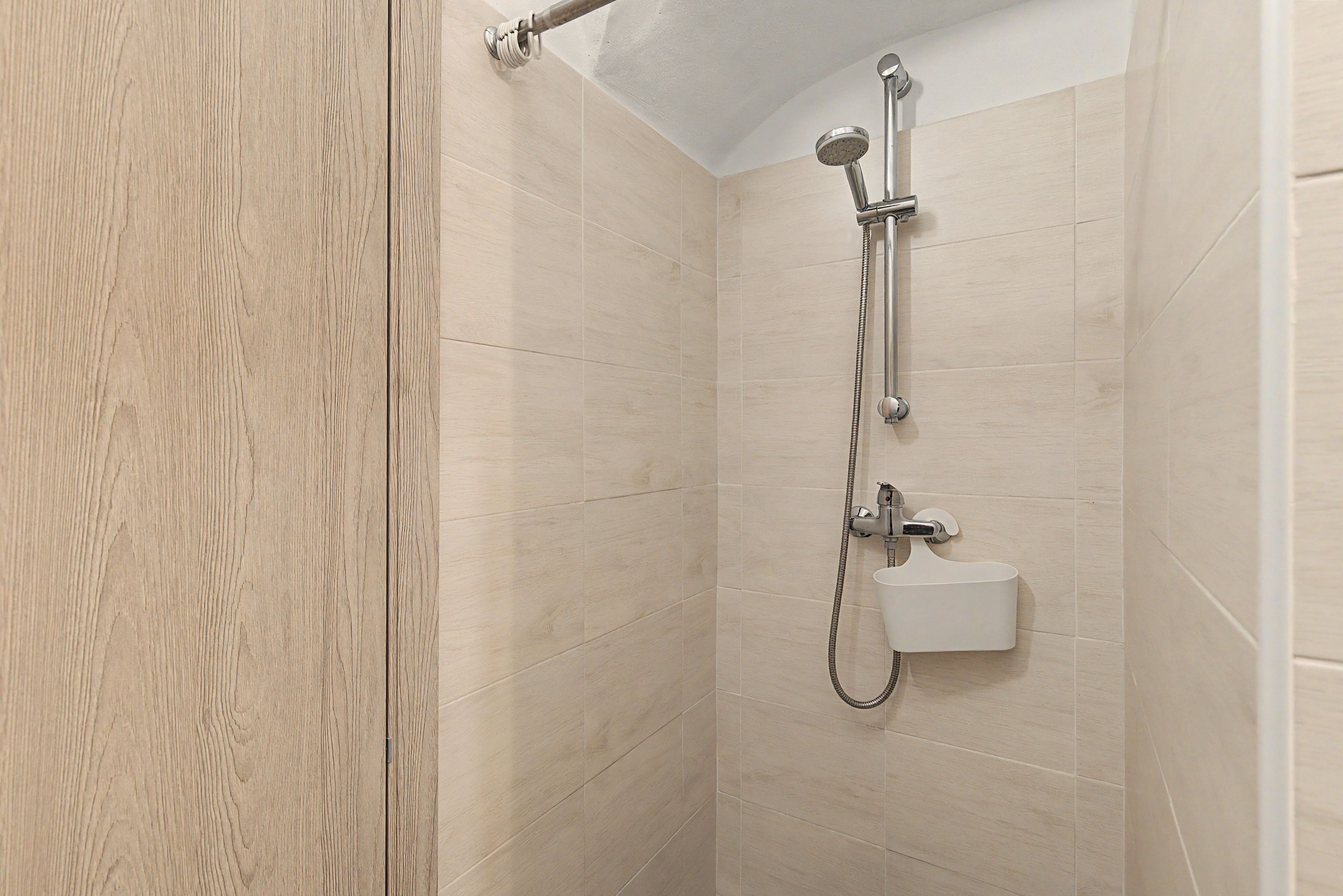 Eine Dusche mit Handbrause und Wandarmatur.