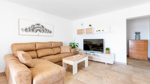 A living room with a sofa, coffee table, TV stand, and decorative items.