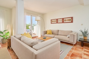 A living room with a sofa, coffee table, and a lamp. There is a sliding glass door leading to an outdoor area. - Holiday home with stunning sea views, private garden, shared pool & Wi-Fi (La Herradura)
