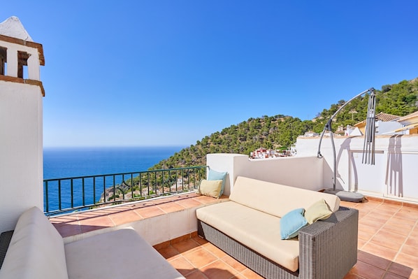 A balcony with a sofa, a small table, and a lamp.