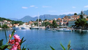 Un pueblo costero con barcos amarrados a lo largo del muelle, una iglesia y montañas al fondo.