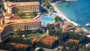 Vista aérea de un hotel frente al mar con piscina, playa y océano.