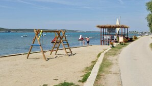 A beach with a swing set, a small hut, and a clear view of the sea. - Coastal Escape in Ljubač (Ljubac)