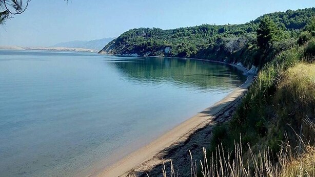A calm lake with a sandy beach and a forested hill in the background. - Coastal Escape in Ljubač (Ljubac)