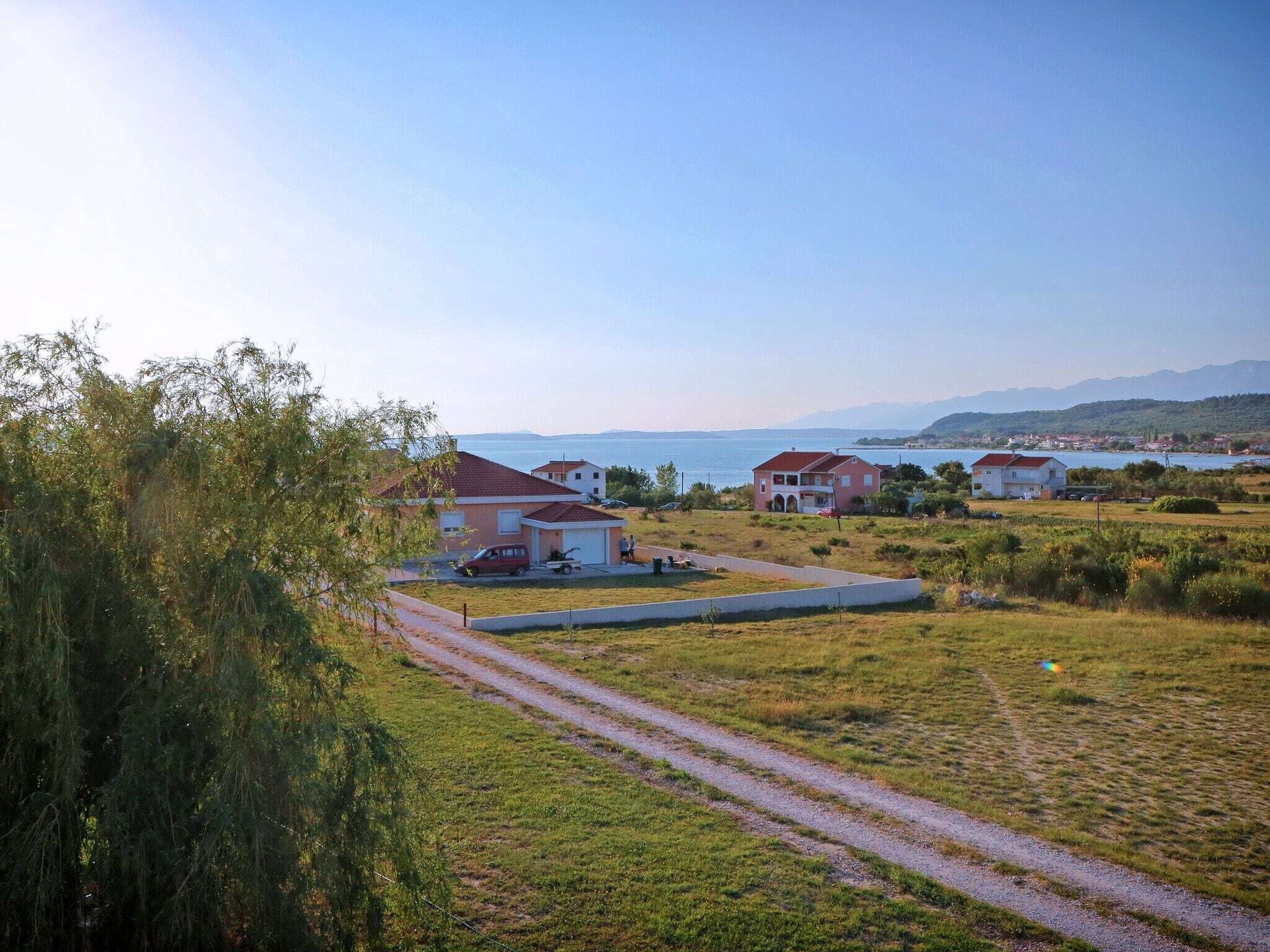 A coastal residential area with houses, a clear sky, and a view of the sea.