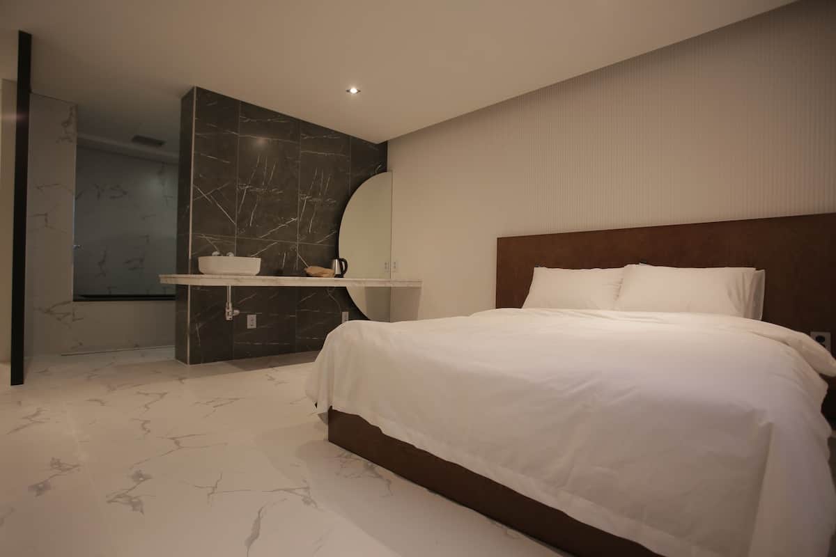 A modern bedroom with a large bed, a built-in vanity, and a marble floor.