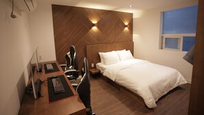 A modern hotel room with a wooden headboard, a single bed, a desk with a computer, and a chair. - Hotel Seven Step (Siheung)