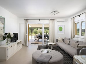 Un salon moderne comprenant un canapé, un pouf et un coin repas avec des chaises et une table.